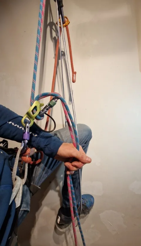 4. Remonter au maximum le nœud autobloquant et installer sa longe réglable dans le mousqueton de travail. Mettre le pied dans la pédale. Une main sur l’autobloquant, venir se remonter sur la pédale en avalant la corde après le rappel de charge